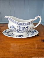 Side profile of gravy boat on underplate displaying blue Nordic pattern and handle detail