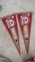 Pair of triangular red felt pennants laid flat on floor
