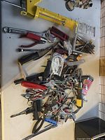 Overview of pile showing caulking gun, hand tools, hardware pieces