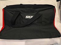 Front view of SKIL black and red canvas tool bag showing logo, handles and exterior pocket