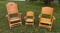 Front view of three foldable wooden rocking chairs on lawn