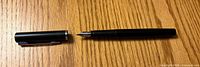 Pen uncapped showing nib and separate cap on wooden surface