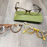 Three eyeglass frames and case laid out