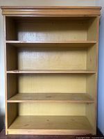 Front view showing entire pine bookcase with three shelves and back panel