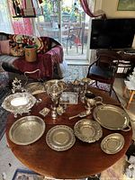 Overall lot on round table showing all silver and silver-plated serveware pieces
