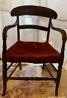 Front view of mahogany Sheraton armchair showing red velvet seat and turned legs