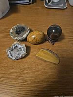 Group view of jasper egg, stone sphere on stand, two geodes, tiger's eye slab