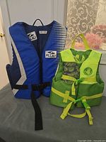 Blue Fluid adult life jacket and green Body Glove child life jacket side by side