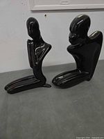 Both black glazed ceramic abstract sculptures side by side