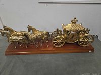 Full view of gold-tone horse-drawn carriage clock on wood base