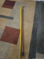 Full length view of cane beside measuring tape showing length and overall appearance