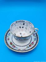 Teacup on saucer front view showing floral border, gilt rim and interior playing card motif