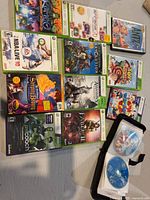 Overall lot showing six Xbox 360 game cases, one Disney DVD case, and open binder with two loose movie discs