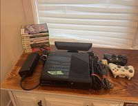 Front view of console, Kinect, controllers, power brick, cable bundle and stack of game cases