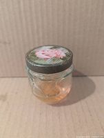 Oblique view of glass jar showing rose-shaped form and remaining gelée