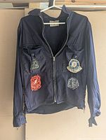 Full view of jacket showing color, zipper, laced cuffs/sides, and placement of four patches