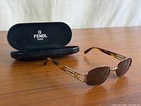 Sunglasses angled with case behind on tabletop