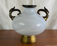 Front view of white vase with gold handles and foot