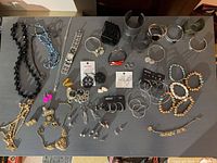 All jewelry pieces and Guess watch laid out on table