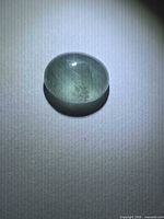 Front lit view of oval aquamarine cabochon showing color and inclusions