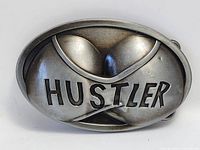 Front of oval Hustler belt buckle showing raised design and text