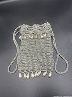 Front view of metallic silver crochet pouch with pearl fringe