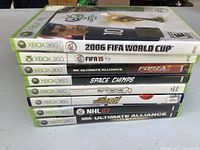 Stack of eight Xbox 360 game cases showing spines and titles