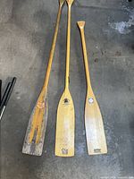 Three wooden canoe paddles laid out side by side