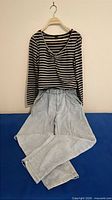 Front view of striped ROMWE top on hanger over light wash Garage jeans folded
