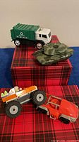 All four toy vehicles grouped: garbage truck, tank, monster truck, dune buggy