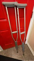 Full view of both crutches leaning against red door