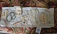 Overview of entire lot on tissue paper, showing necklaces, bracelet, brooch, earrings in box