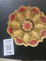 Top view of amber pressed glass bowl showing floral pattern and scale tag 176