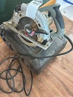Side view of circular saw resting on case showing blade, guard and power cord
