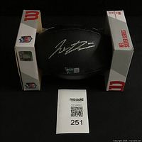 Overall view of signed black Wilson mini football in box with lot tag
