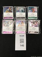 Six sealed bundles of One Piece trading cards on black background, lot tag 146 visible