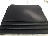 Stack of four black mouse pads top view