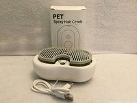 Pet spray hair comb atop charging base with USB cable and retail box