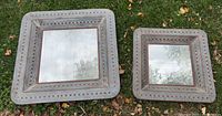 Both square mirrors side by side on grass, showing size difference and design