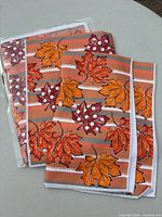 Two sealed packs of autumn leaf kitchen towels, each pack containing two towels