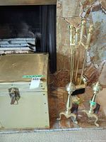 fireplace tool set on stand beside trunk and part of andirons