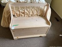 Front view of solid pine storage bench showing spindle backrest and hinged lid