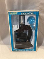 Front of boxed edu-science microscope showing microscope and blue magnifier in Styrofoam insert