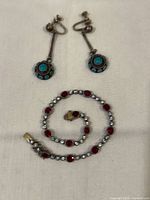 Earrings above coiled rhinestone bracelet on cloth background