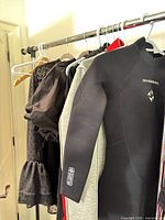 Rack with Dive & Sail wetsuit and mixed tops visible