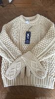 Sweater laid flat with matching mittens displayed on top