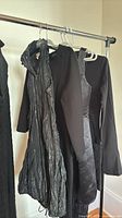 Multiple black dresses hanging on rack showing variety of styles and fabrics