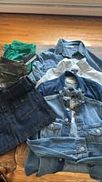 Pile displaying all seven clothing items including denim jackets, skirt, corduroy and camouflage pants
