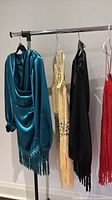 Rack with four beaded fringe dresses in teal, gold/champagne, black, red