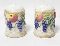 Front view of both ceramic shakers showing fruit design and perforated tops